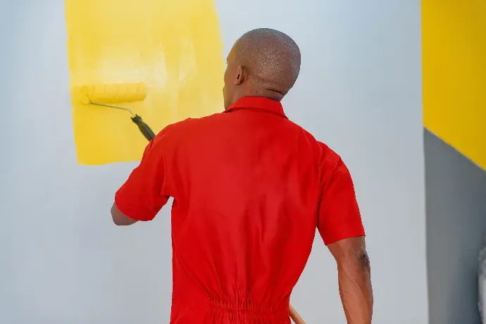 a man painting a wall with yellow paint